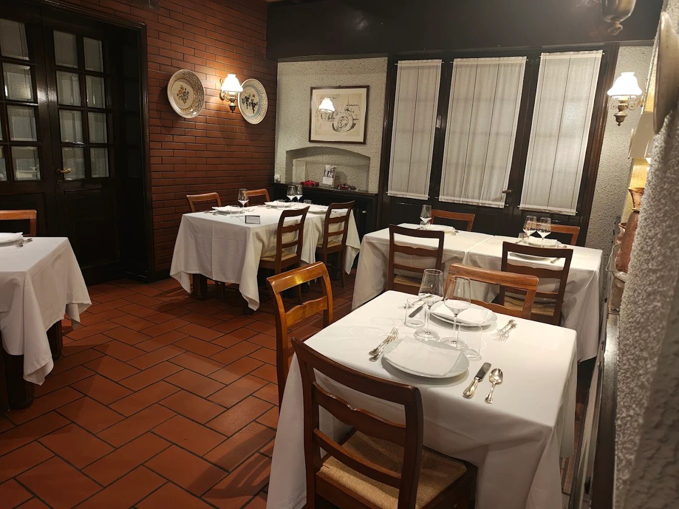 Sala con muro in mattoni, piatti in ceramica e porte in legno scuro